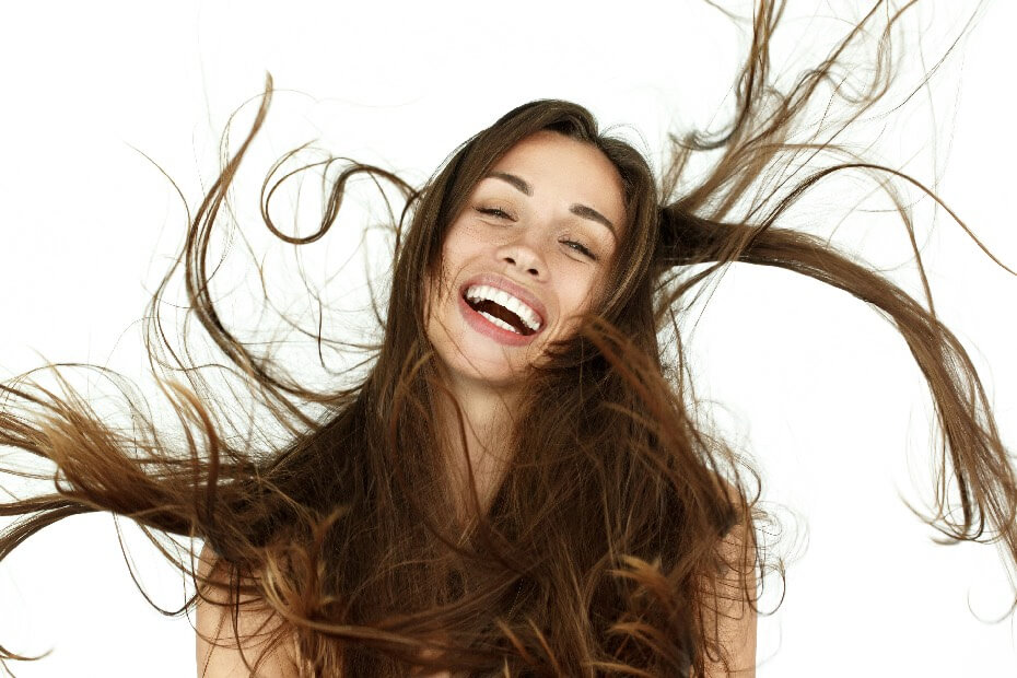 Mujer de frente sonriendo con el cabello alrededor, sobre 5 tips para minimizar los daños causados por el uso excesivo de herramientas térmicas