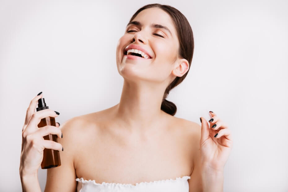Mujer de frente sonriendo y sujetando un sellador de maquillaje, sobre tips de maquillaje para lucir radiante en la playa