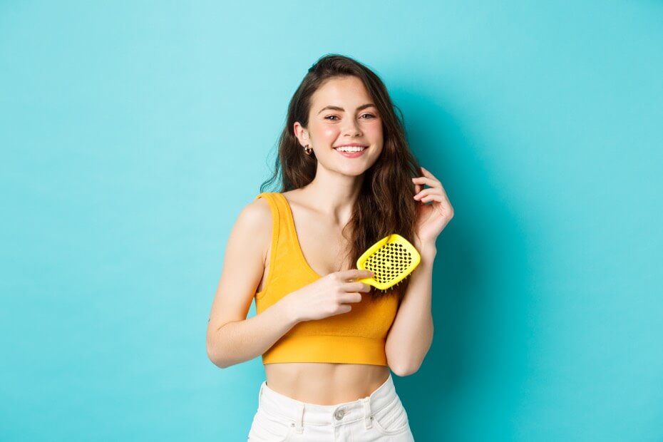 Mujer de frente texturizando su cabello con un peine, sobre los 6 pasos para obtener unas ondas playeras perfectas