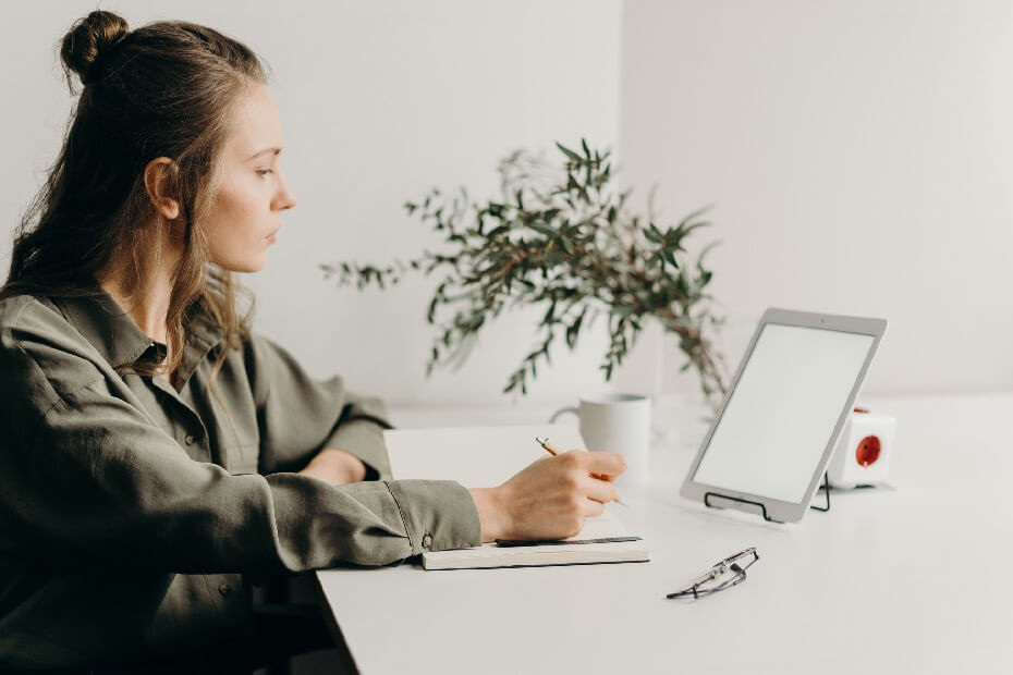 Mujer sentada en su escritorio haciendo home office, mientras adapta su rutina de belleza al trabajo desde casa
