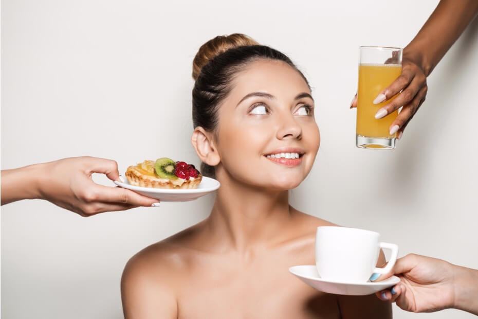 Mujer siendo ofrecida un jugo de naranja, un café y postre, sobre alimentación y nutrición para una piel radiante