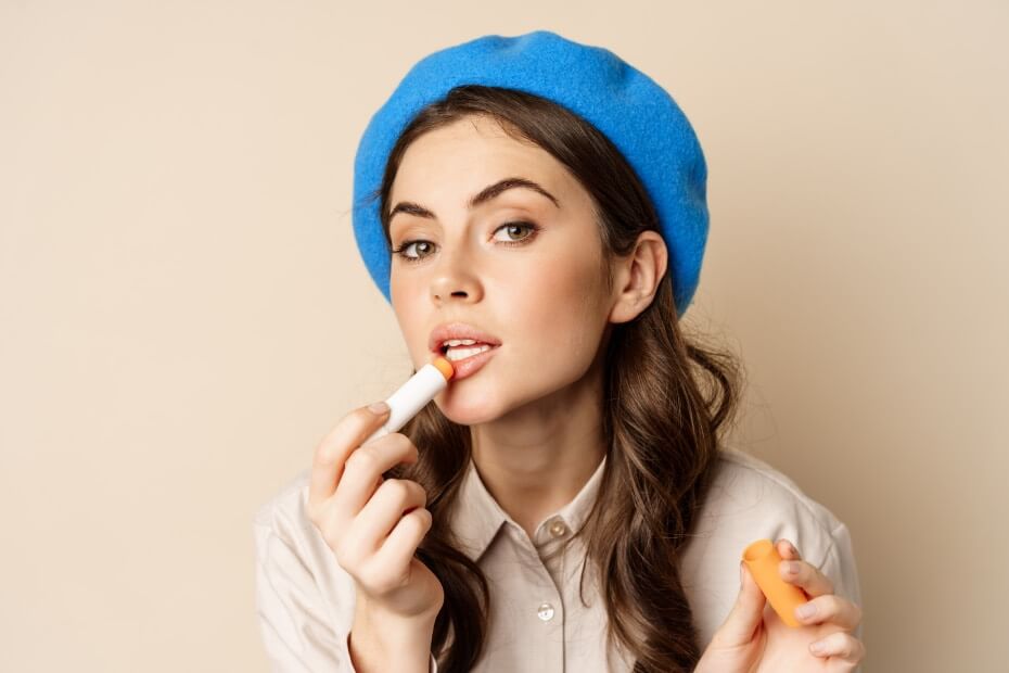 Dama de frene aplicándose un bálsamo labial, sobre domina el regreso a clases con estilo: 7 Tips para un maquillaje back to school