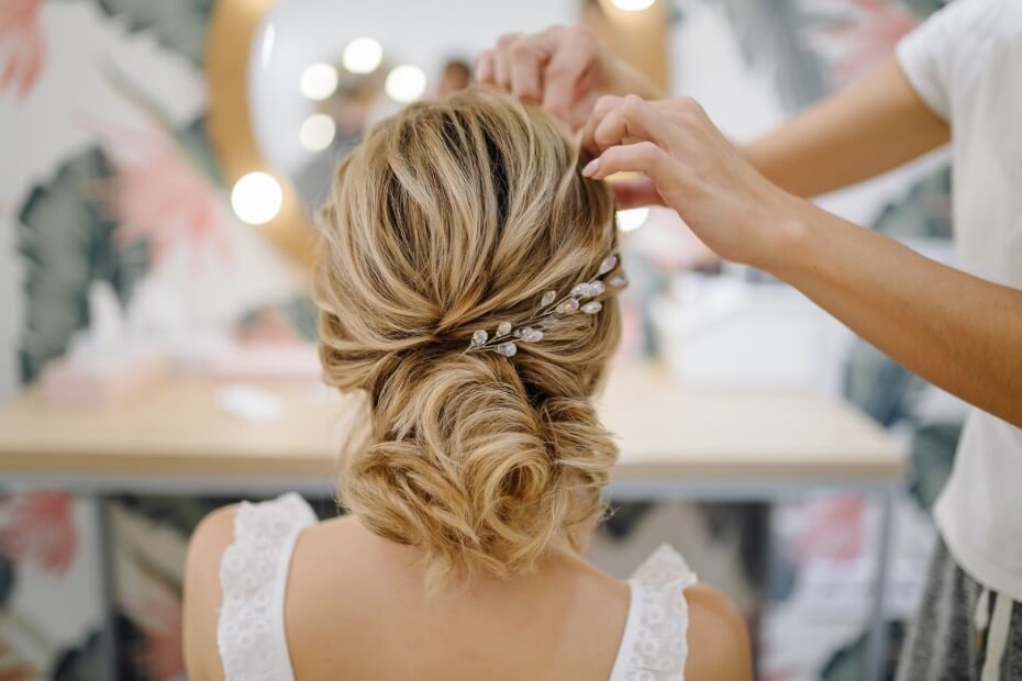 Mujer realizando peinado recogido en clienta rubia por Foriu